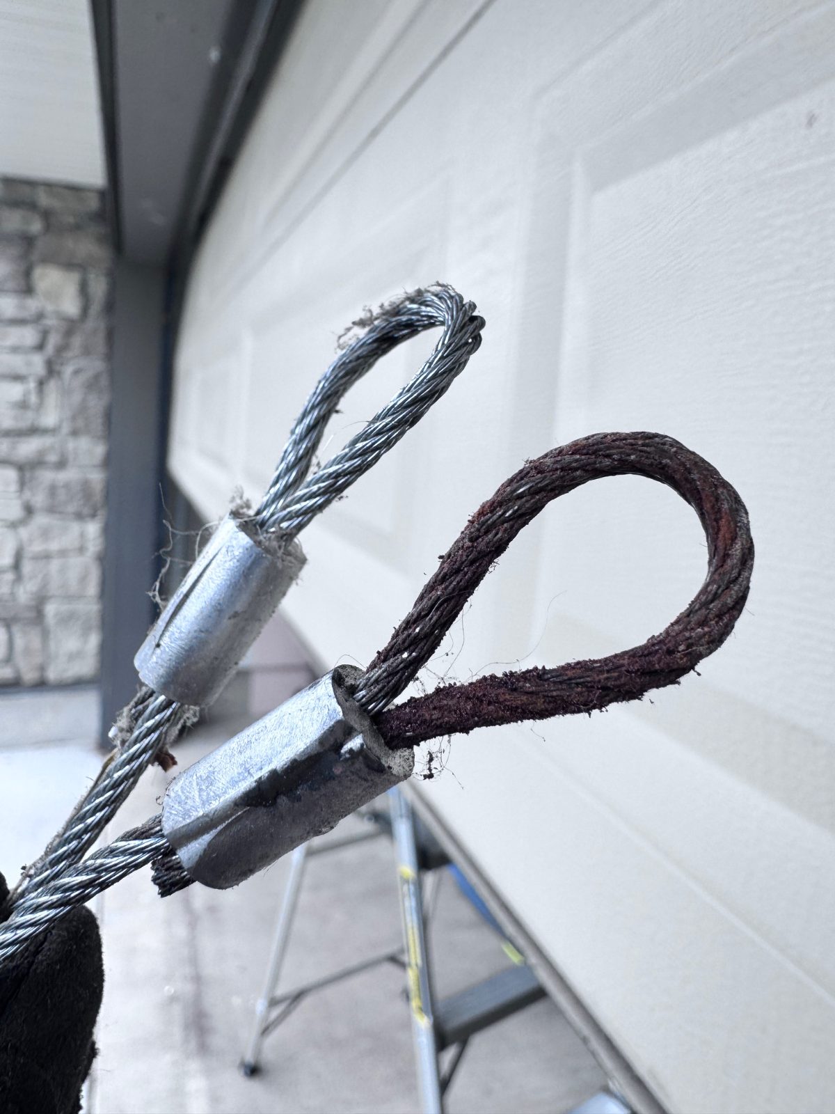 POCO Garage Doors technician on a ladder performing a 21-point garage door inspection on a residential sectional door
