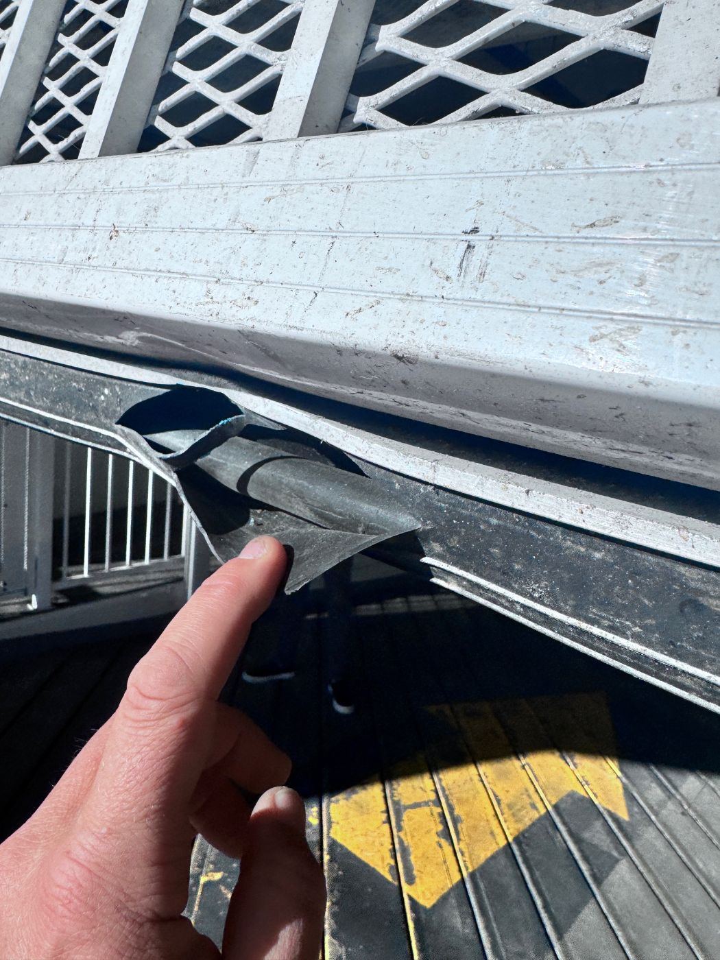 Torn rubber bottom seal on a commercial garage door pulled away from the metal retainer at a Port Coquitlam loading dock — identified during a POCO Garage Doors maintenance visit