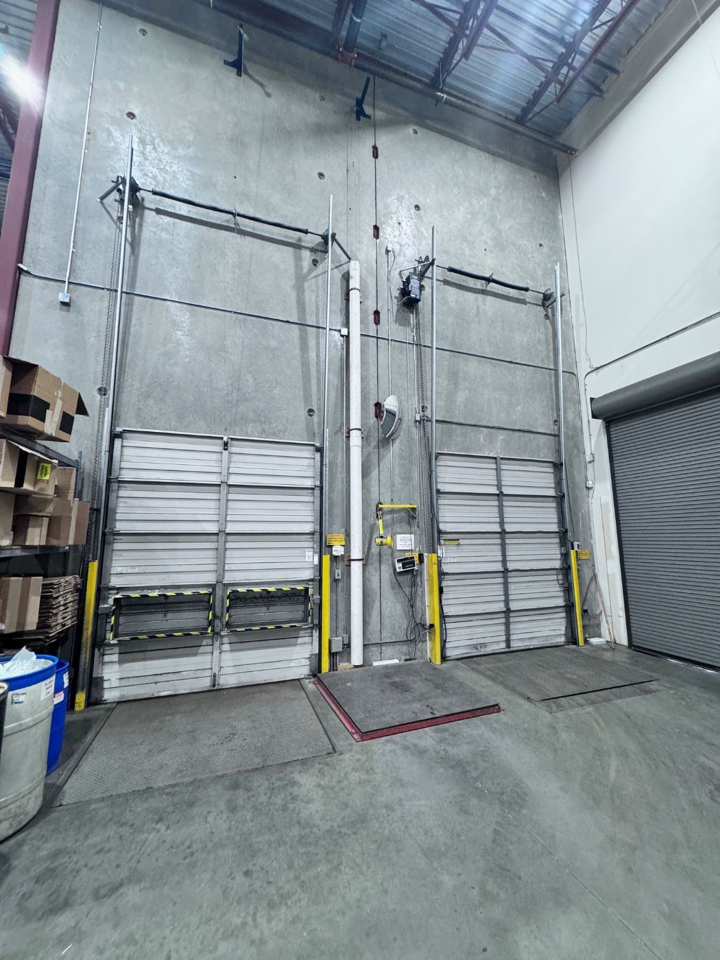 Two tall commercial overhead loading dock doors at a Coquitlam warehouse photographed during a POCO Garage Doors scheduled maintenance contract visit