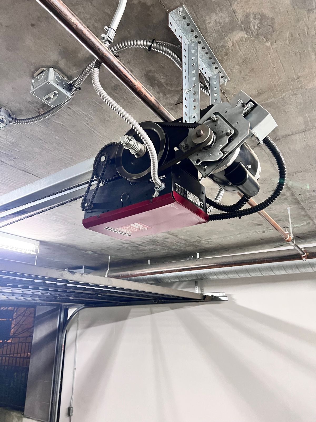 Commercial jackshaft garage door opener mounted on a Coquitlam parkade ceiling, serviced by POCO Garage Doors