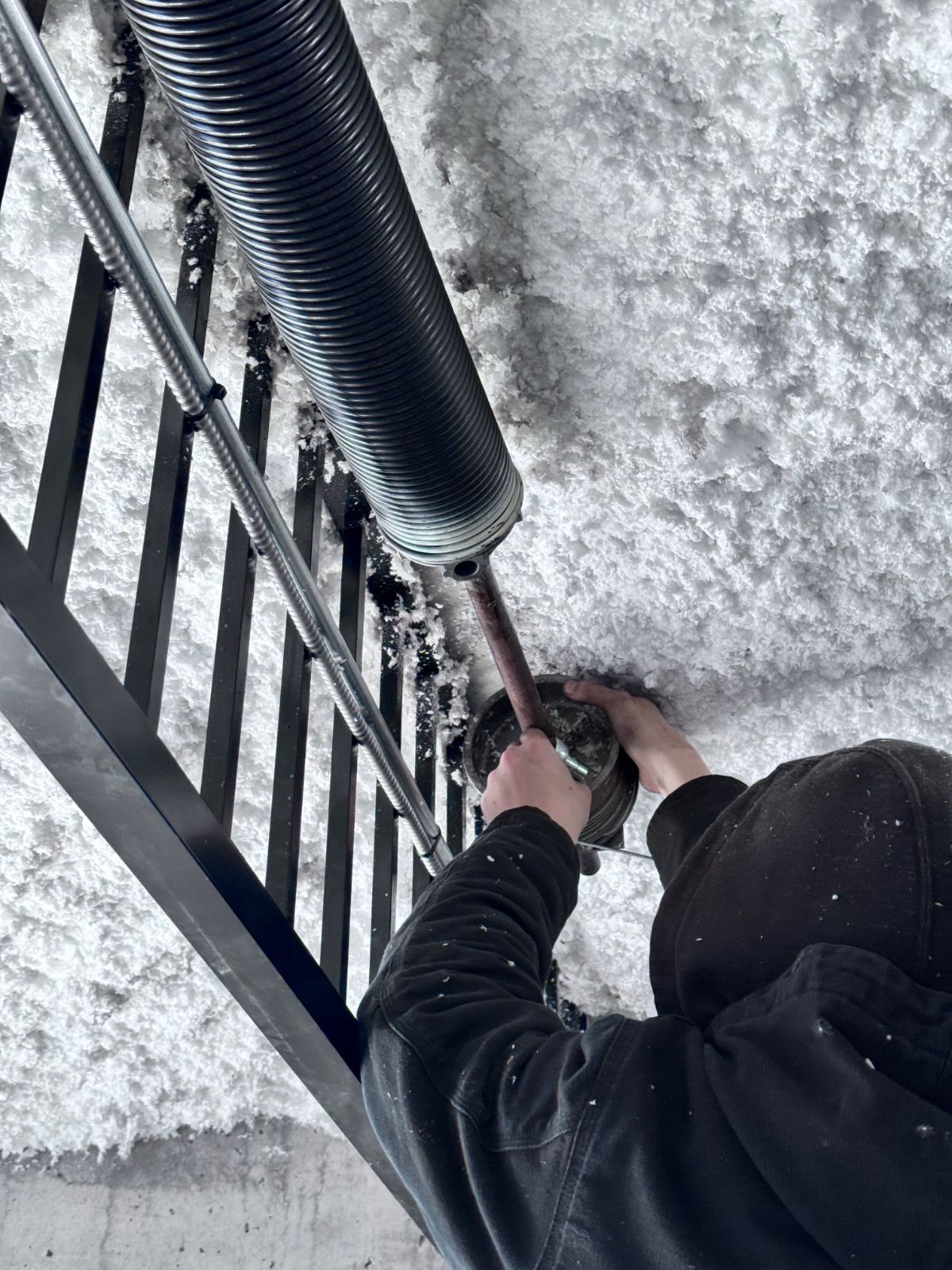 POCO Garage Doors technician installing a high-cycle commercial torsion spring on a Coquitlam warehouse door