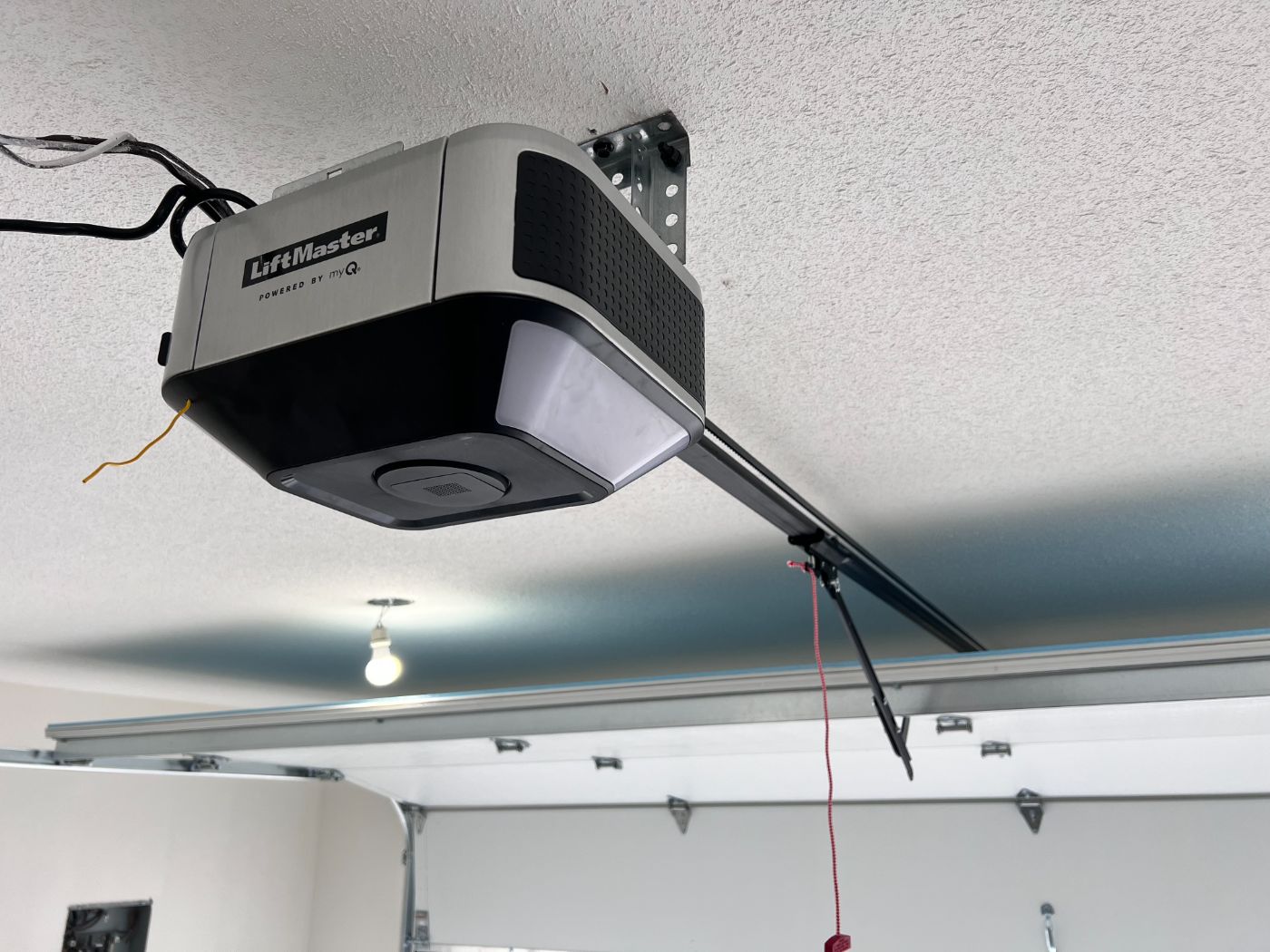 New LiftMaster myQ smart garage door opener freshly installed on the ceiling of a Port Coquitlam home with red emergency release cord visible