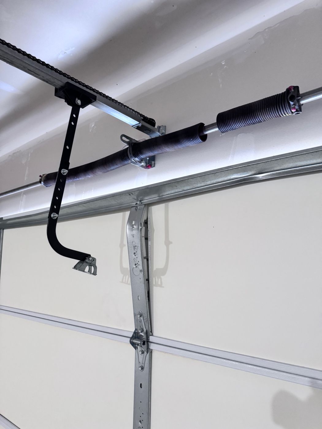 Broken torsion spring replacement on a Port Coquitlam garage door — new spring installed on shaft above the door