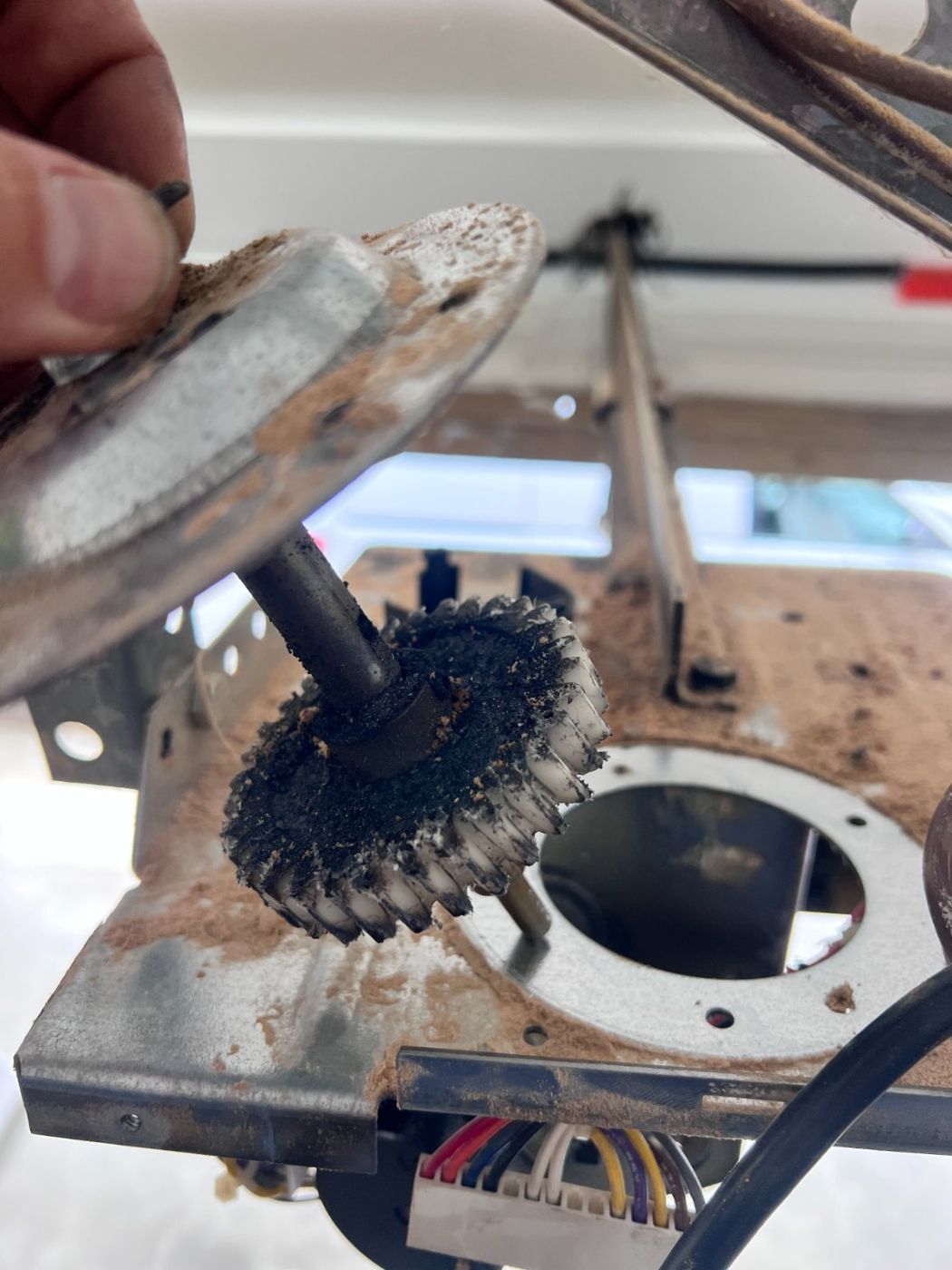 Stripped white nylon drive gear caked in grease and shavings inside an opened LiftMaster opener housing at a Port Moody home