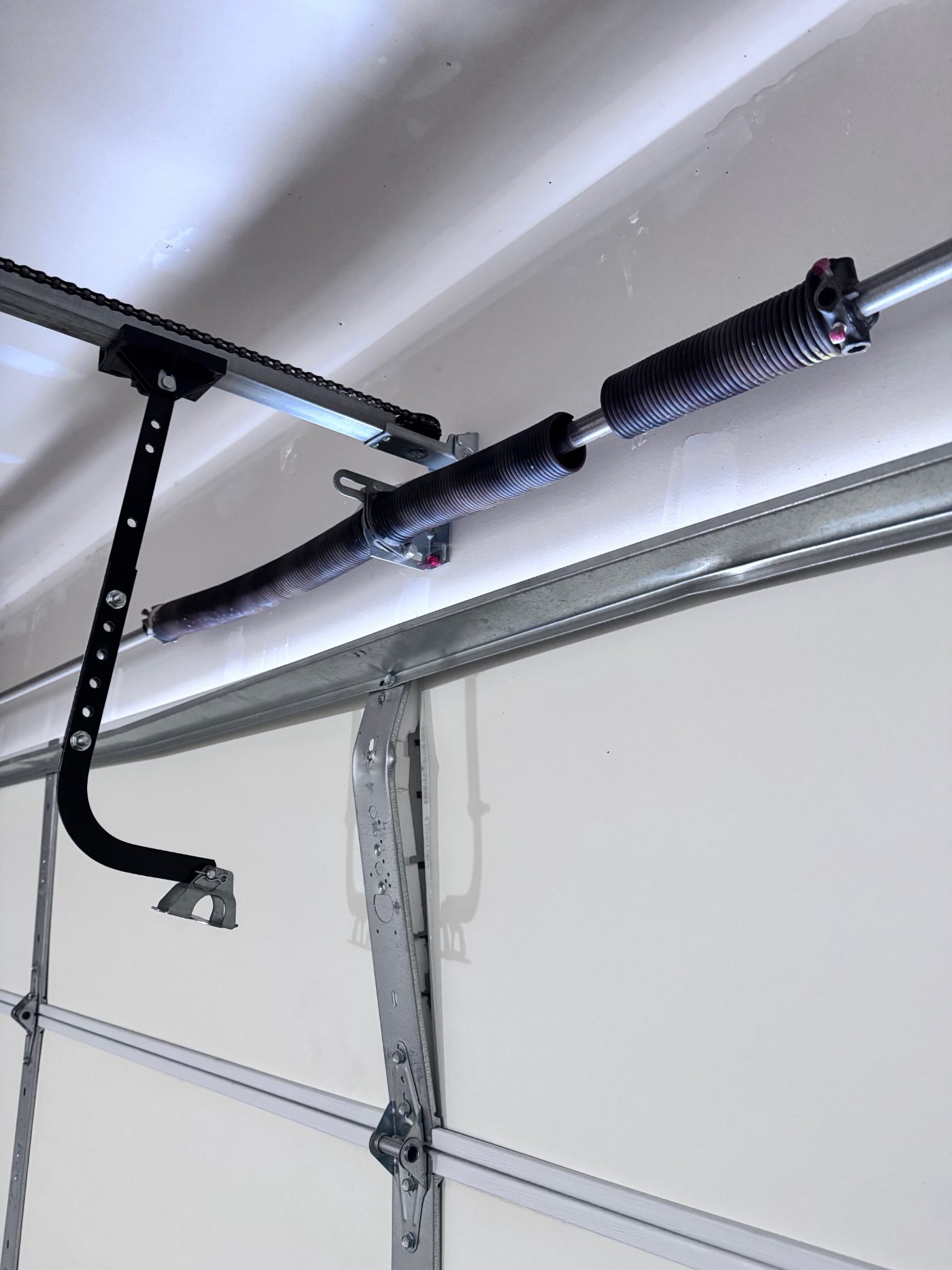 Snapped torsion garage door spring with visible gap above a residential garage door in Coquitlam BC awaiting same-day replacement by POCO Garage Doors