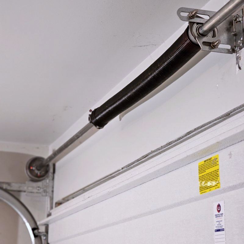 Extension spring stretched along the horizontal track of a residential garage door