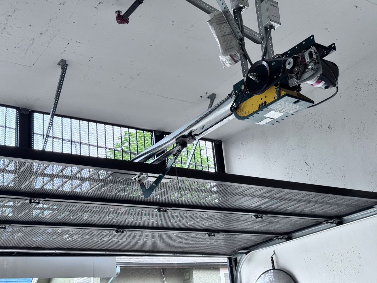 Old commercial garage door opener mounted to the ceiling of a Tri-Cities strata parkade — inspected during a POCO scheduled maintenance visit