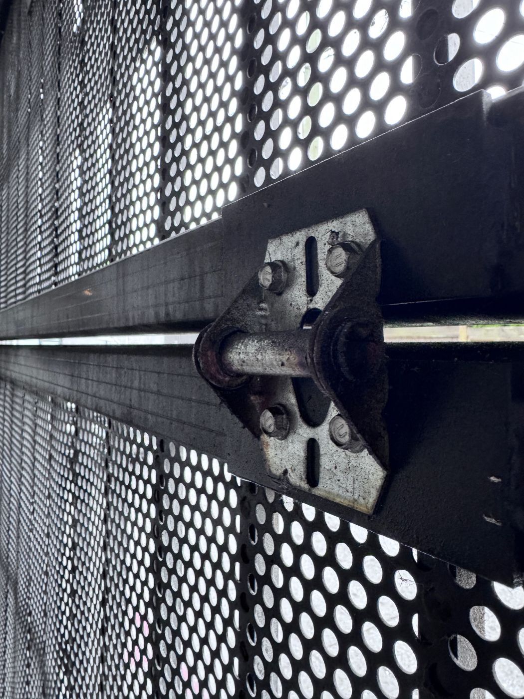 Corroded gate hinge bracket on a strata mesh parkade door in Coquitlam found during a POCO Garage Doors preventive maintenance inspection