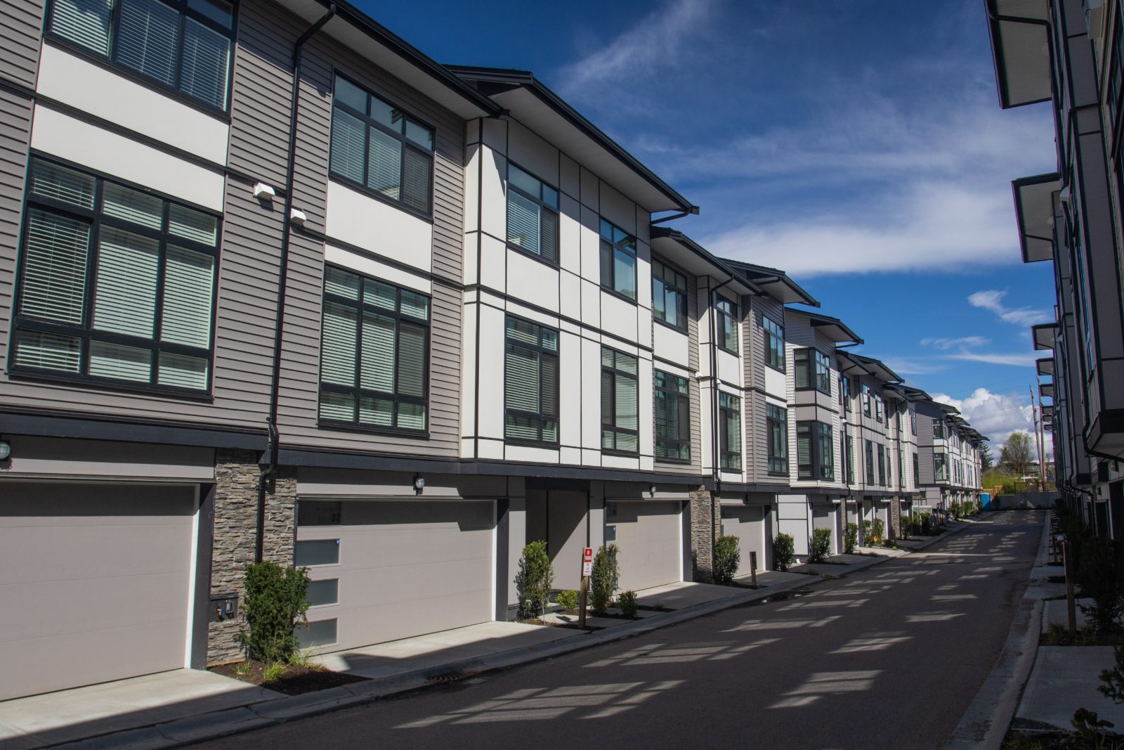 Row of modern Tri-Cities townhomes with matching garage doors installed by POCO Garage Doors