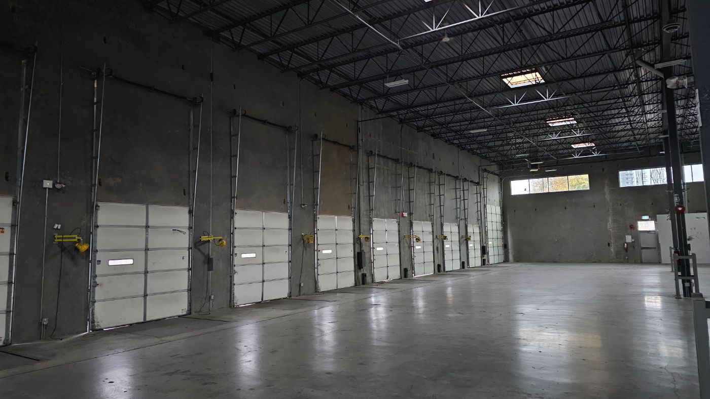 POCO Garage Doors technician repairing a sectional warehouse loading dock door in Coquitlam BC